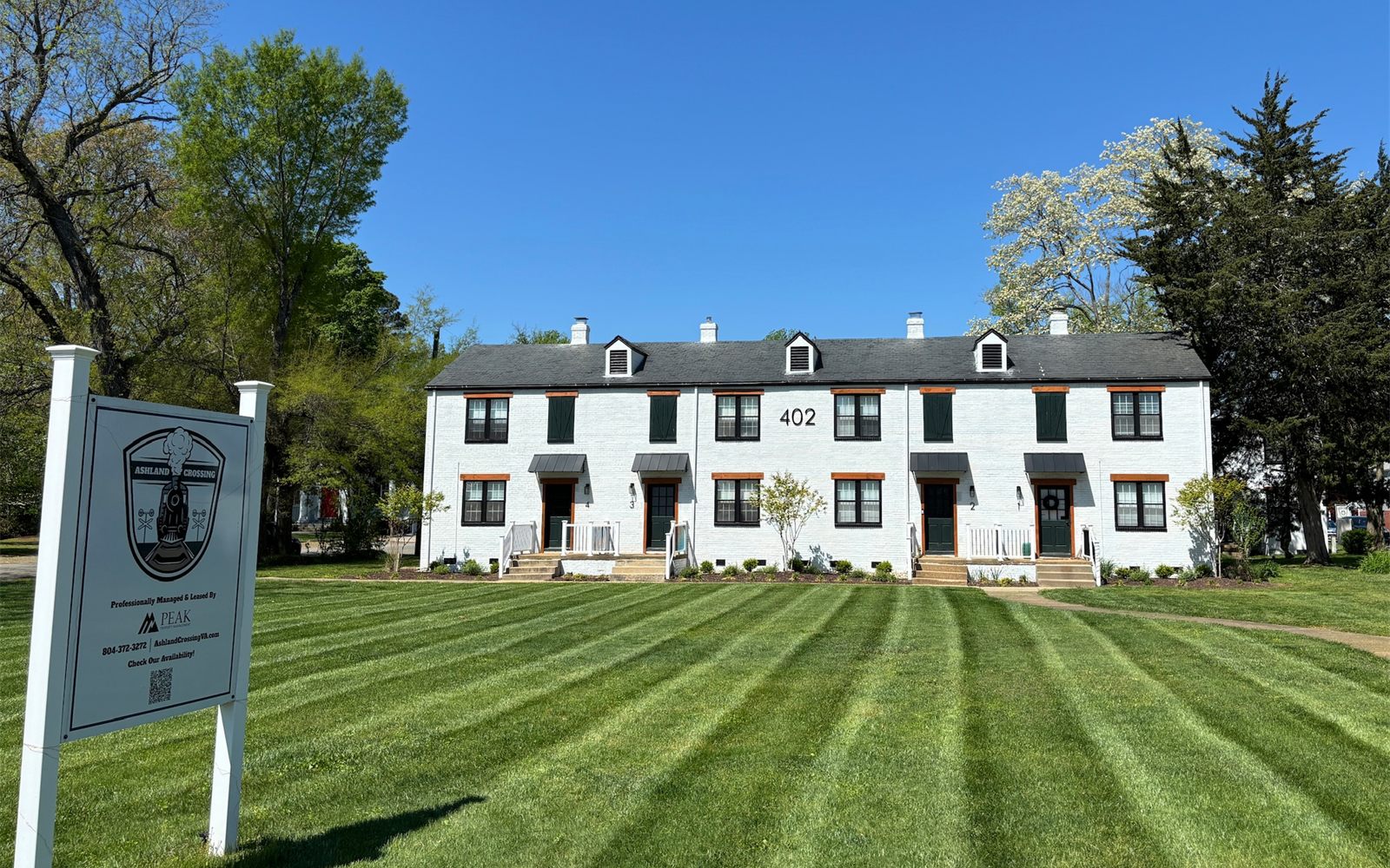 Ashland Crossing: a white-painted brick townhome building with its leasing sign on the front lawn